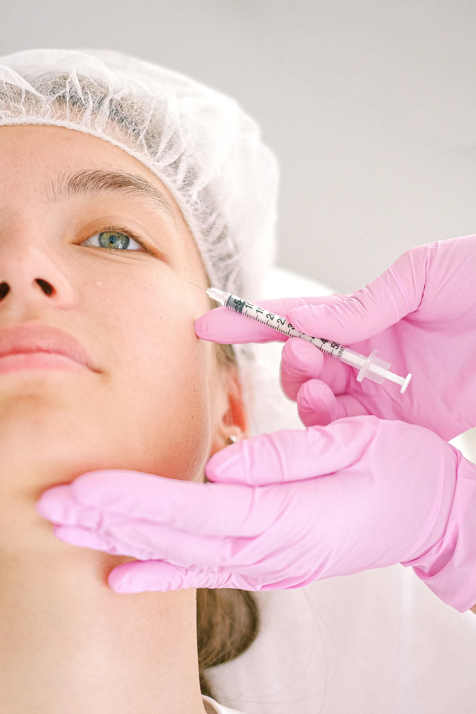 Close-up of a clinician administering a facial injection treatment in a clinical setting.