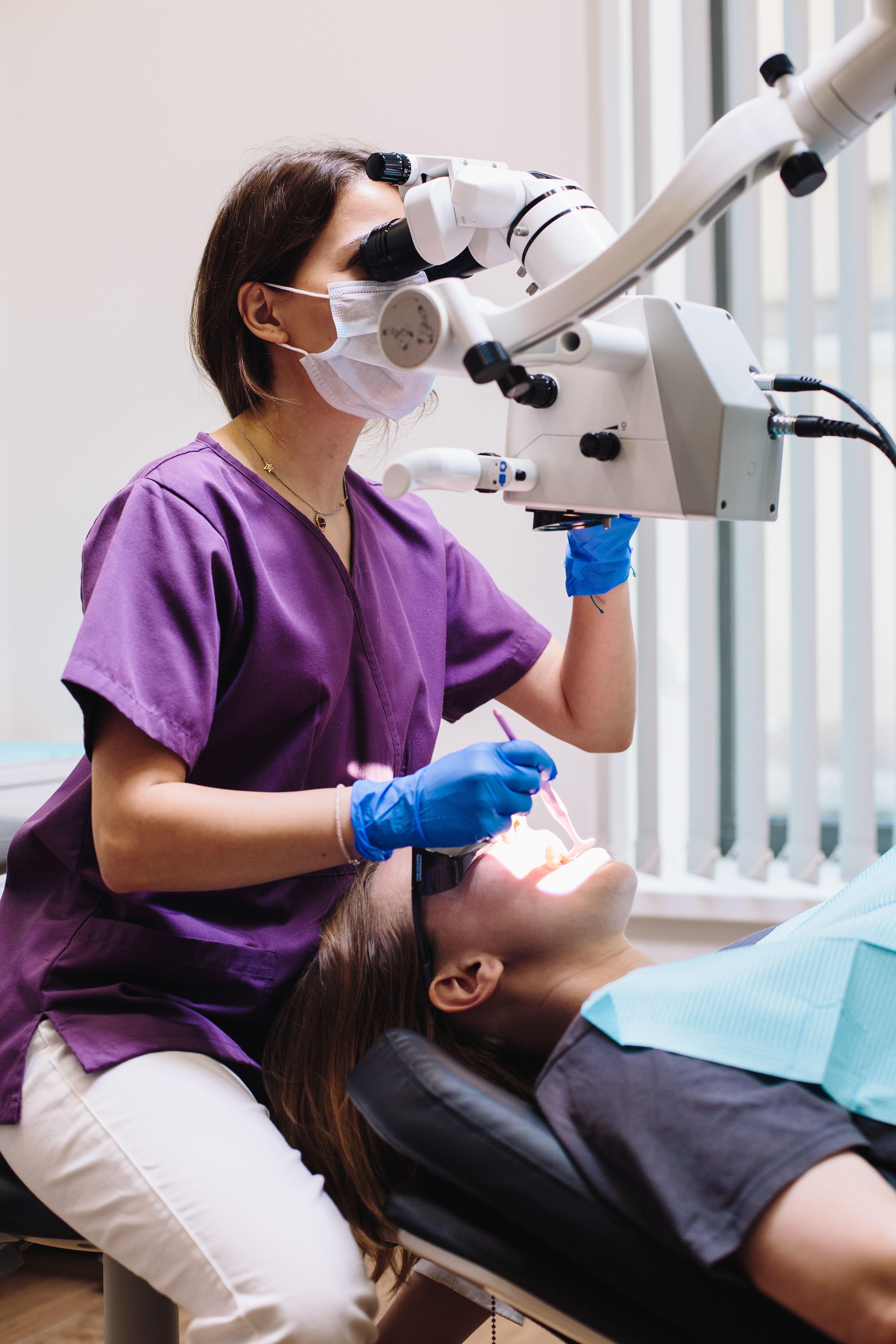 Dental professional using a microscope during endodontic treatment in a clinic.