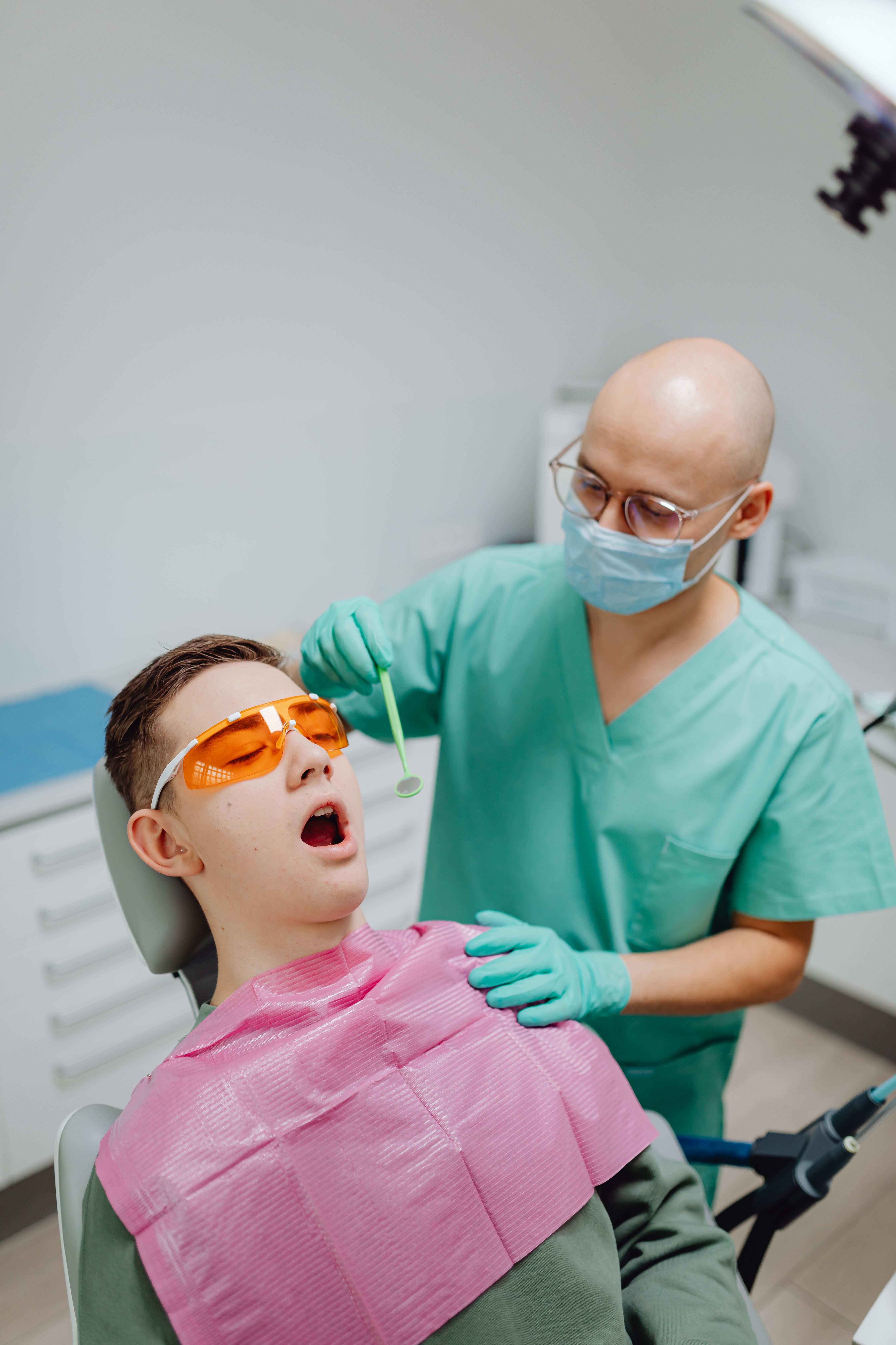 Dentist performing a routine check-up for a patient wearing protective eyewear.