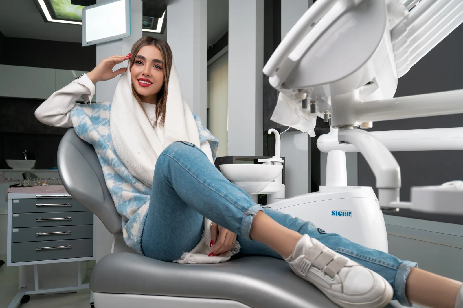 Smiling dental patient seated in a modern clinic chair after cosmetic dental care.