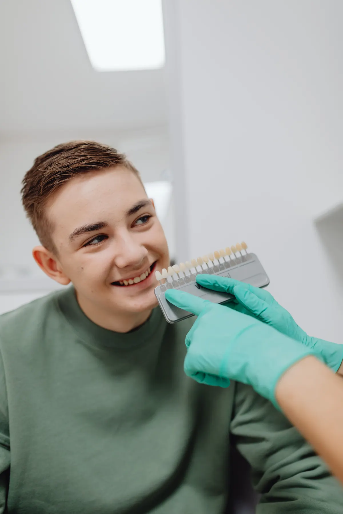 Dental shade guide being compared with a patient's teeth during whitening consultation.