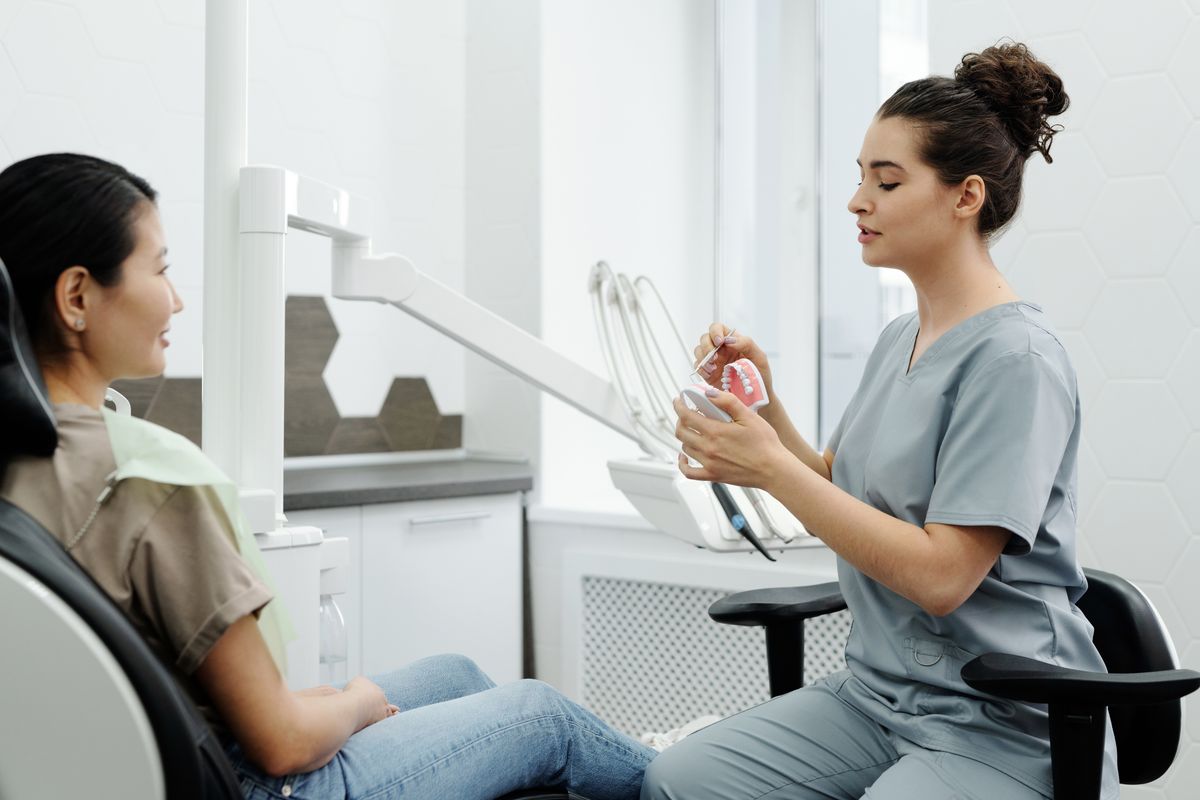 Dentist explaining dental care with a model during consultation; illustrative stock image.