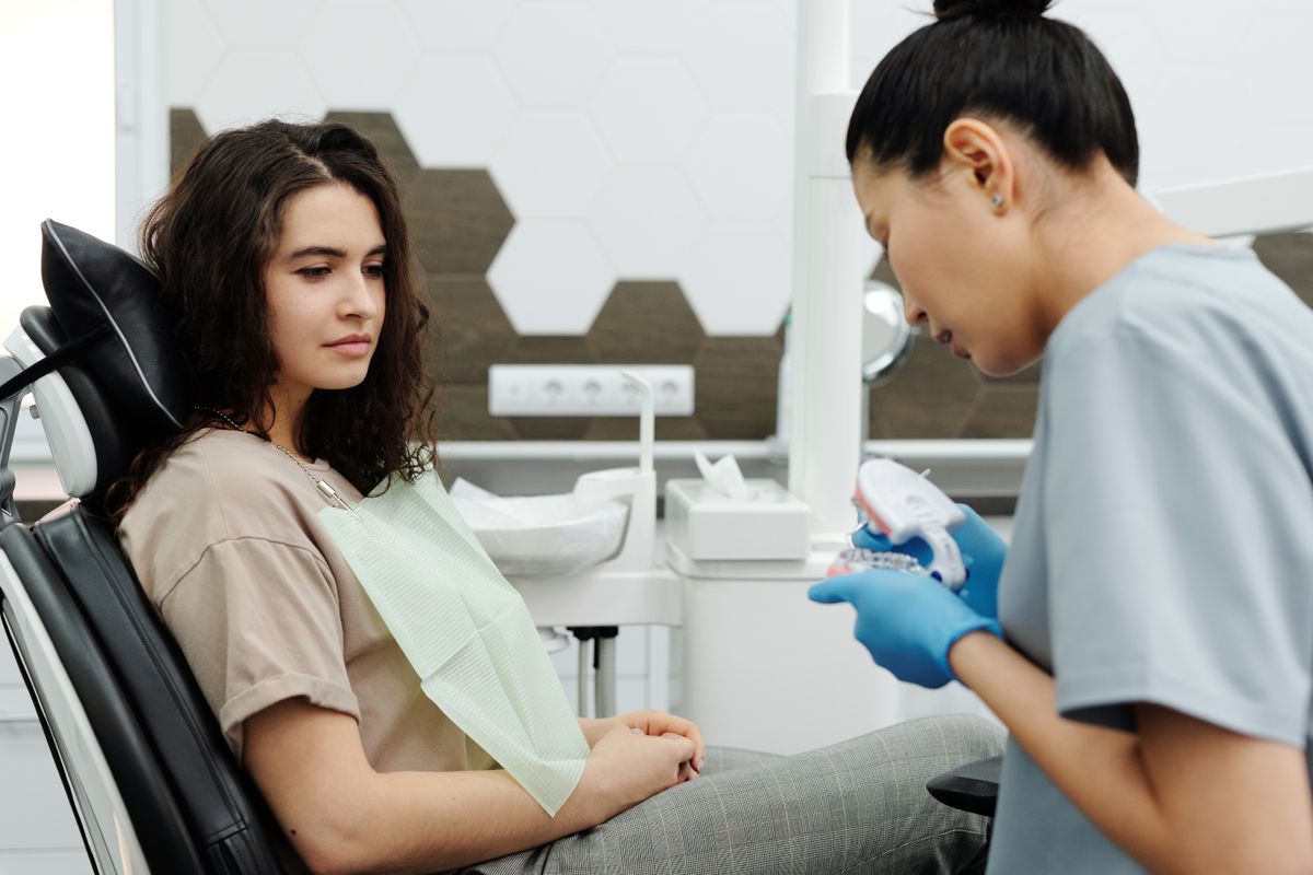 Dentist showing a dental model to a patient during consultation.