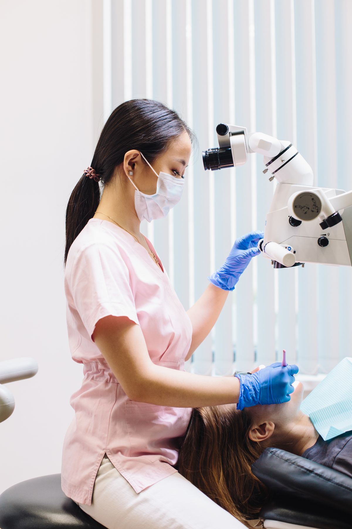 Dental professional working with a microscope during treatment.