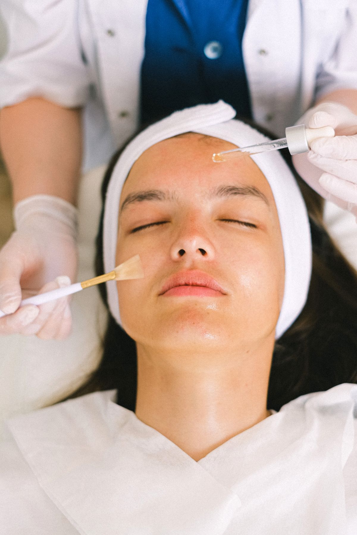 Professional applying a facial skin care product; illustrative stock image.