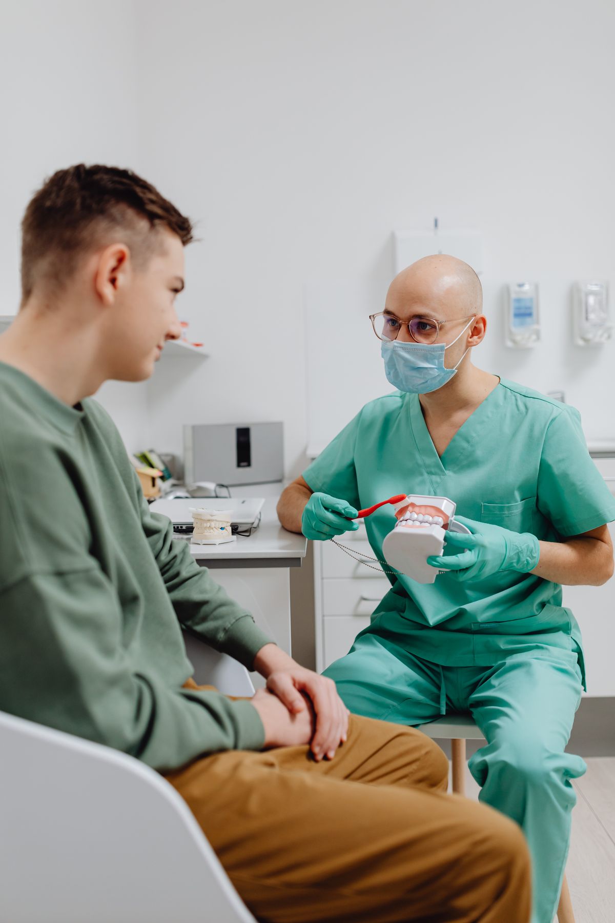 Dentist discussing oral hygiene with a patient using dental models.